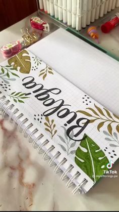 an open notebook with the word boooo written on it next to some pens and pencils