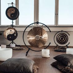 gongs and pillows are arranged on the floor in front of large windows