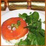 a white plate topped with a piece of salmon and greens