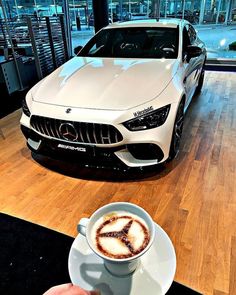 a cup of cappuccino next to a white car