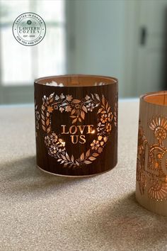 A wood and glass lantern carved with hearts and leaves saying love us lit with a candle. Perfect decor for weddings, and engagements