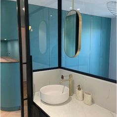 a bathroom with blue walls and white counter tops, gold fixtures and a round sink