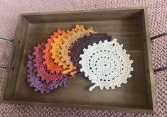 four crocheted umbrellas sitting on top of a wooden tray