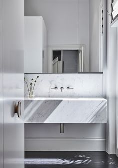 a white bathroom sink sitting under a mirror next to a window with sunlight streaming through it