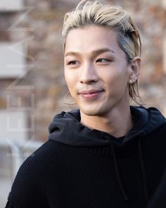 a young man with blonde hair wearing a black hoodie and looking at the camera