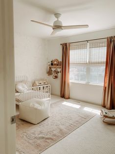 a bedroom with a white bed and beige curtains on the window sill next to it