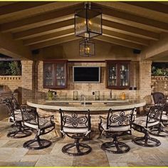 an outdoor bar with chairs around it and a television mounted on the wall behind it