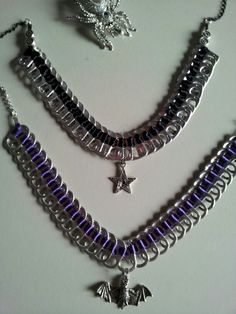 three different necklaces with charms attached on a white surface, one is purple and the other is silver