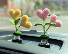 three crocheted flowers in the shape of hearts are sitting on top of a car dashboard