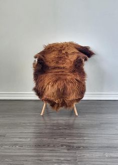 a chair made out of fur sitting on top of a hard wood floor next to a wall