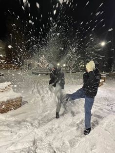 a person throwing snow at a horse in the middle of a snowy field on a cold winter night