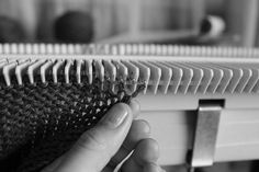 a hand is holding the edge of a piece of woven material in black and white