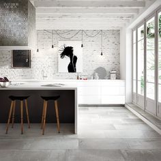 two stools sit in front of a white kitchen island with black and white artwork on the wall