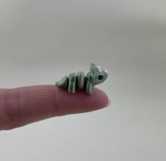 a tiny toy lizard sitting on top of a finger