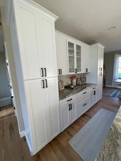 a kitchen with all white cabinets and granite counter tops in the center of the room