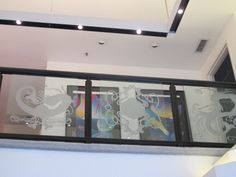 a balcony with glass railings and artwork on the wall