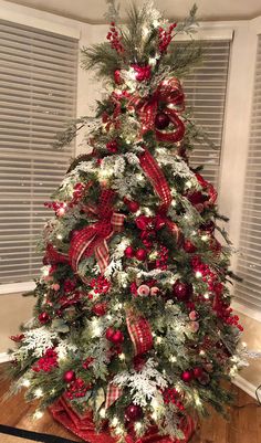 a decorated christmas tree with red and white ornaments, bows and lights on the top