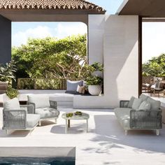 an outdoor living area with couches and tables next to a swimming pool in the background