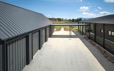 an empty walkway between two buildings with metal roofing on the top and bottom floors