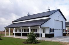 a large white barn with black trim on the roof