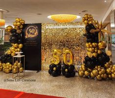 the balloon letters are gold and black in front of a large chandelier that reads 50