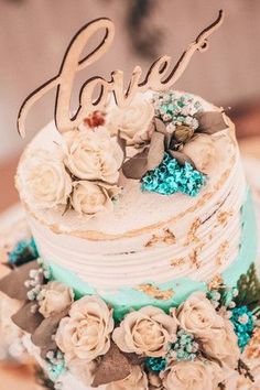 a wedding cake with flowers and the word love on top