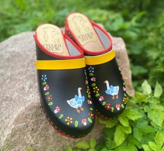 Hand painted leather clogs with a specific Swedish goose and a wreath of flowers and mushrooms on the edge.   The leather above is plain leather which makes the shoe easy to clean and maintain.  The sole is made of alder wood (one of the lightest wood types), and keeps the foot comfortable due to its anatomic pass form and big toe indent. Also, due to the non slip, abrasion resistant rubber sole that is glued on, the clog doesn't make too much noise either.  If you are unsure of the shoe size yo Swedish Clogs, Sunny Sunday, Prestigious Textiles, Wooden Clogs, Cashmere Yarn, Hand Painted Leather, Leather Clogs, Clogs Shoes, Leather Hobo