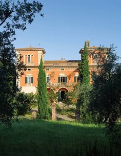 an old brick building surrounded by trees and grass