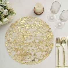 the table is set with silverware and gold place settings for two people to eat