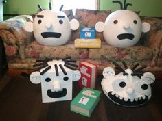 three paper mache heads sitting on top of a table next to boxes and books