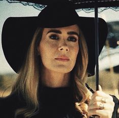 a woman wearing a black hat holding an umbrella