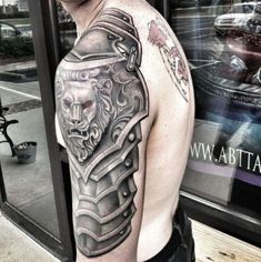 a man with a lion tattoo on his arm and shoulder is standing in front of a store window