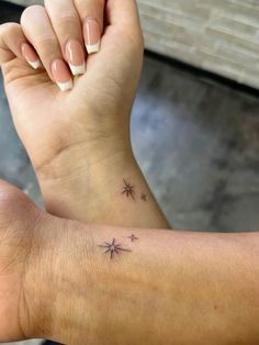 a woman's arm with a small star tattoo on it and her left wrist