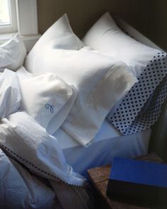 white sheets and pillows on a bed with polka dot pillowcases in the corner