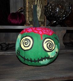 a painted pumpkin sitting on top of a wooden table