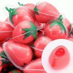 plastic strawberries with green leaves and water droplets on them, sitting in a container