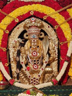 an idol is surrounded by flowers and other decorations on the table in front of it