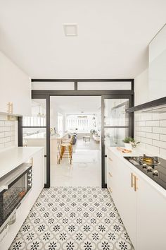 a kitchen with black and white tile flooring next to an open door leading into the dining room