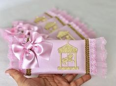 a hand is holding a pink and gold gift wrapped in ribbon with a horse on it