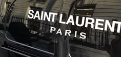 the reflection of saint laurent paris on the side of a black car with white lettering