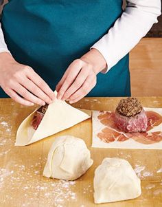 a woman in an apron is making dumplings on a wooden table with other food items