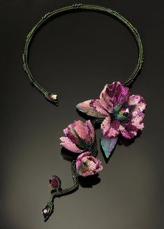 a necklace with flowers and beads is shown on a black surface, in the shape of a flower