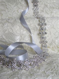 "Sparkling silver bridal sash adorned with rhinestones. Securely fastened onto a quality double faced satin ribbon which ties into a bow and drapes down the back of your wedding dress. Perfect finishing touch for your wedding attire! Please make your choice of rhinestone trim length, ribbon colour, no ribbon or hook and eye closure from the drop down menus. Contact me if you have a custom length requirement. Ribbon options to purchase: You may purchase just the rhinestone trim ( no ribbon ) The Elegant Silver Bedazzled Sashes, Elegant Silver Bedazzled Sash, Elegant Bedazzled Silver Sashes, Elegant Bedazzled Silver Sash, Silver Bedazzled Bridal Belt For Wedding, Silver Bridal Accessories For Party, Silver Bridal Accessories With Sashes For Party, Silver Sashes For Bridal Party Accessories, Wedding Sash Belt