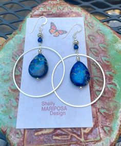 Silver hoop earrings with blue jasper stones. I am over the moon about these beauties! They are large and eye-catching but not too heavy! The stones are royal blue jasper. These earrings are 2 1/2 inches long and 1 1/2 inches wide. The French earwires are sterling silver. All my jewelry comes gift boxed with a custom Shelly Mariposa Design butterfly card ready for gift giving, whether it is a gift for you or someone special. Your satisfaction is very important to me. I make every effort to incor Nickel-free Blue Small Hoop Jewelry, Blue Bohemian Small Hoop Jewelry, Bohemian Blue Small Hoop Jewelry, Blue Small Hoop Earrings With Matching Set, Handmade Blue Hoop Jewelry, Round Lapis Lazuli Gemstone Earrings, Blue Sodalite Jewelry With Natural Stones, Blue Sodalite Jewelry, Blue Wire Wrapped Hoop Earrings For Gift