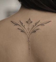 the back of a woman's shoulder with a small flower tattoo on her left side