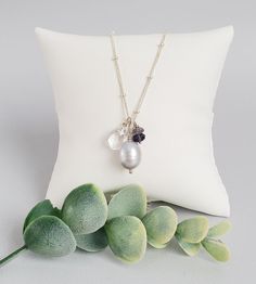 Wear both shimmer and sparkle with this gray pearl iolite cluster pendant. A beautiful freshwater pearl, with silvery luster, is surrounded by sparkling gemstones. A small stack of classic blue iolite and a clear drop of quartz draw the eye with pretty faceting.



Floating over beaded chain, this pendant securely closes with dainty beads and handmade hook clasp. It's a timeless, detailed piece you're sure to wear again and again. Gray Pearl Necklace For Gift, Gray Pearl Necklace For Gifts, Gray Dangle Jewelry For Gifts, Sterling Silver Gray Dangle Jewelry, Gray Sterling Silver Dangle Jewelry, Gray Pearl Pendant Jewelry As Gift, Gray Pearl Pendant Jewelry Gift, Gray Pearl Pendant Jewelry For Gift, Elegant Gray Necklace Perfect For Gifts