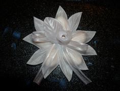 a white flower on a black surface with a button in the center and two smaller flowers attached to it