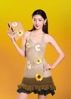 a woman in a dress with sunflowers on it holding a wooden box and looking at the camera