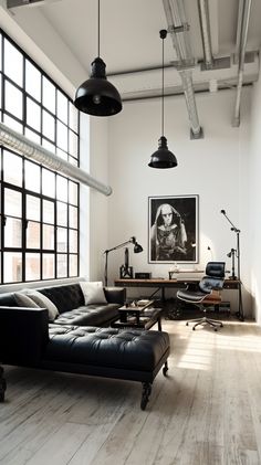 a living room filled with black furniture and lots of windows next to a wooden floor