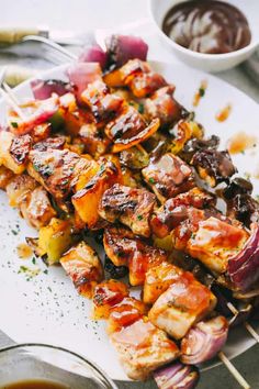 chicken and vegetable skewers on a plate with dipping sauce